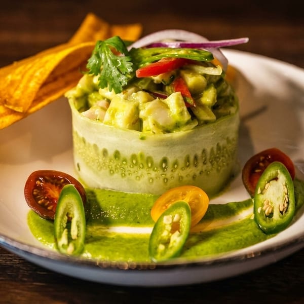 Ceviche in a cucumber ring, garnished with plantain chips, tomatoes, and jalapeños.